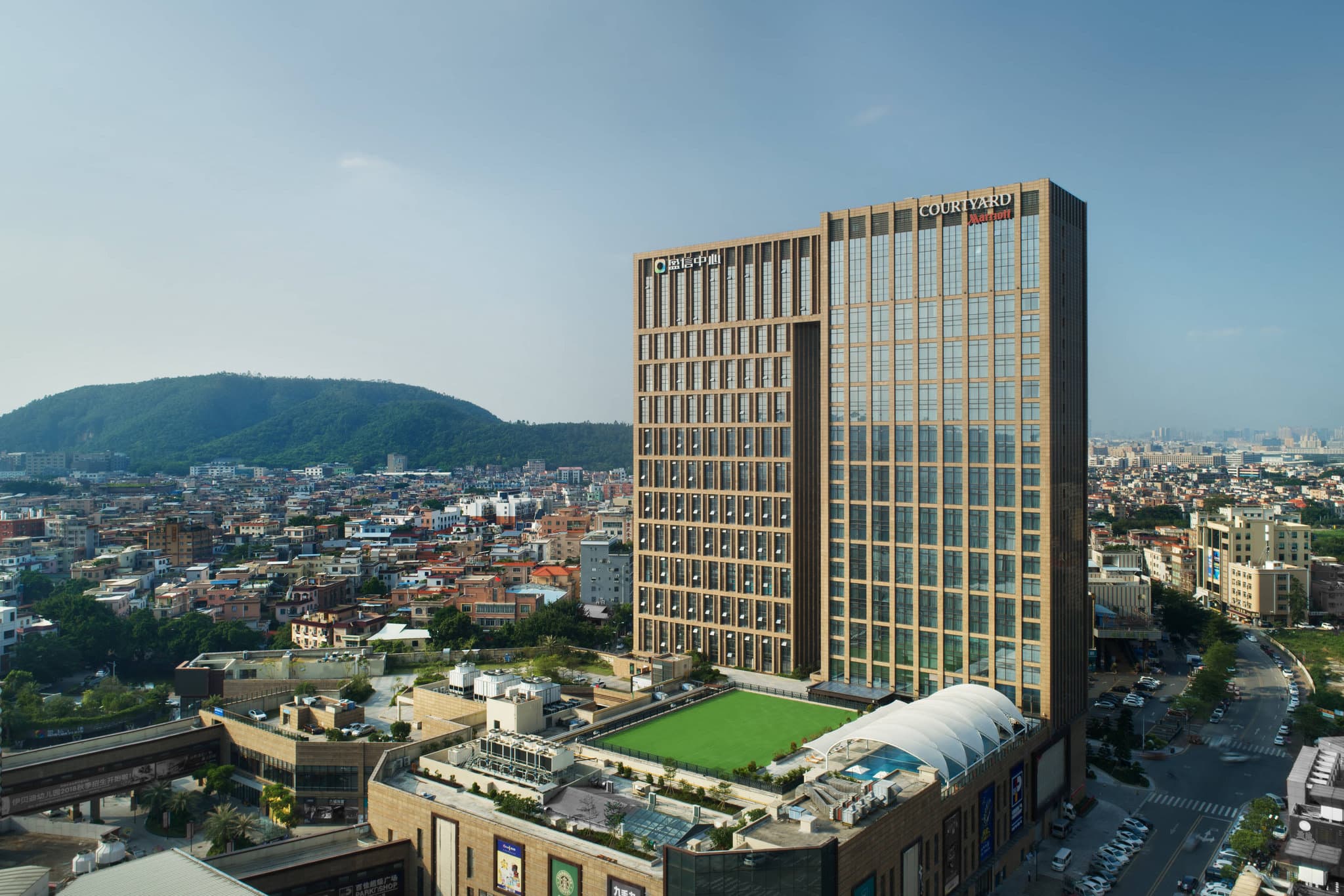 Floor-to-ceiling windows in a Courtyard Shunde Longjiang executive suite overlooking the Foshan cityscape at twilight.