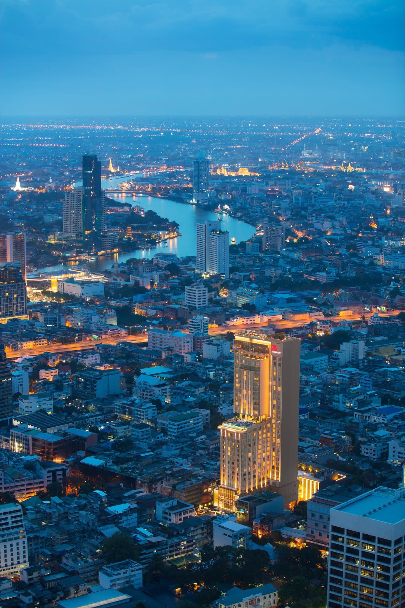 A dramatic dusk view of the 18th-floor infinity pool at Bangkok Marriott Hotel The Surawongse, overlooking the lit-up King Power Mahanakhon skyscraper.