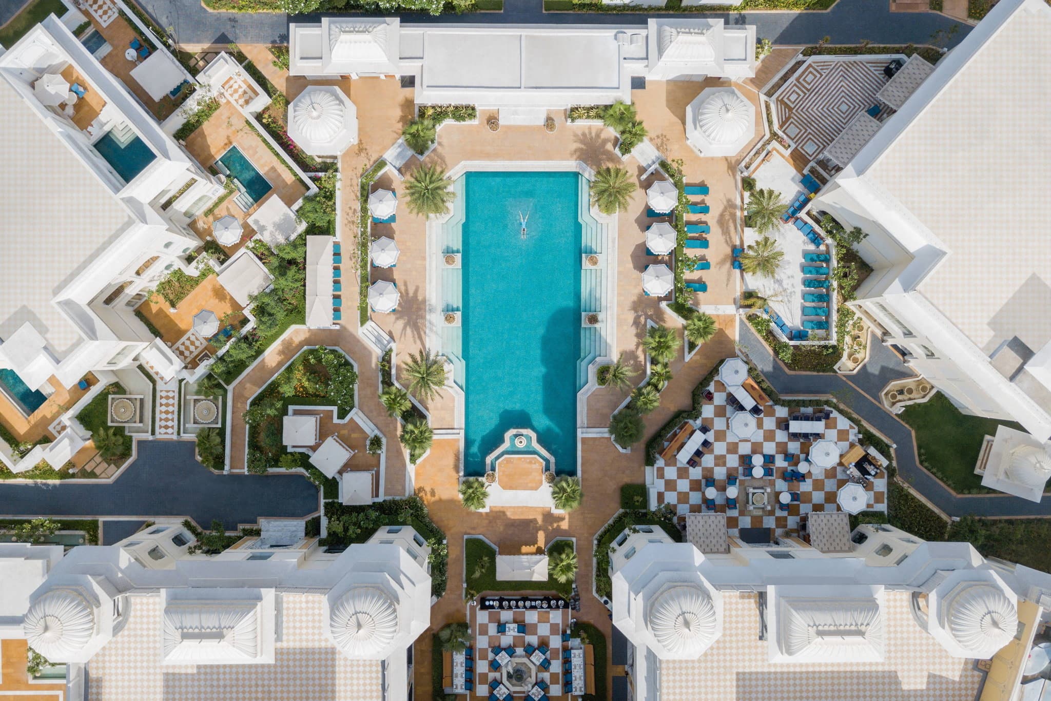 The Leela Palace Jaipur's white façade reflected in the temperature-controlled pool at twilight.