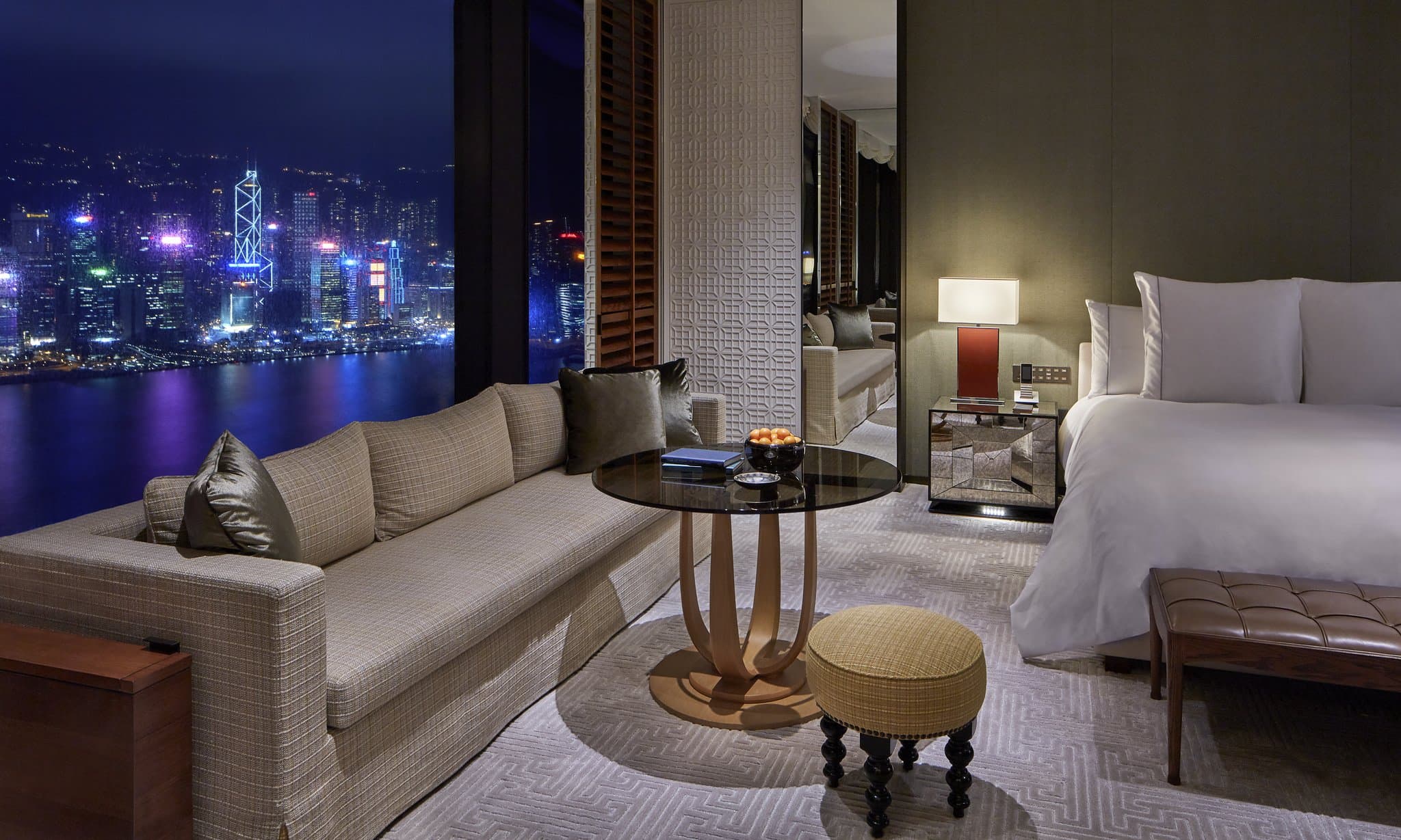 A panoramic view of the Rosewood Hong Kong infinity pool overlooking Victoria Harbour at dusk.