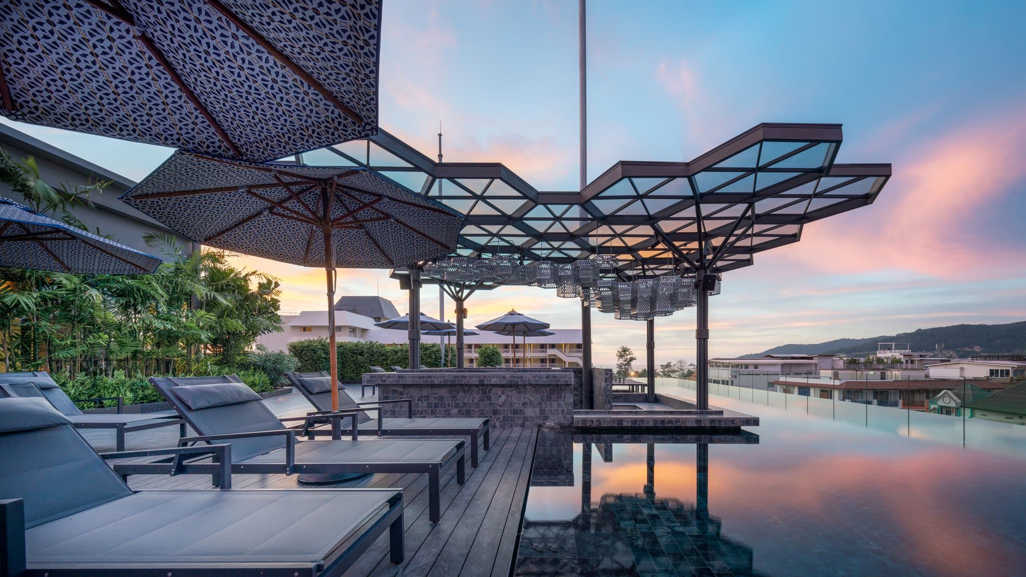 The Cloud rooftop infinity pool at Hotel Indigo Phuket Patong at sunset, overlooking the city skyline.
