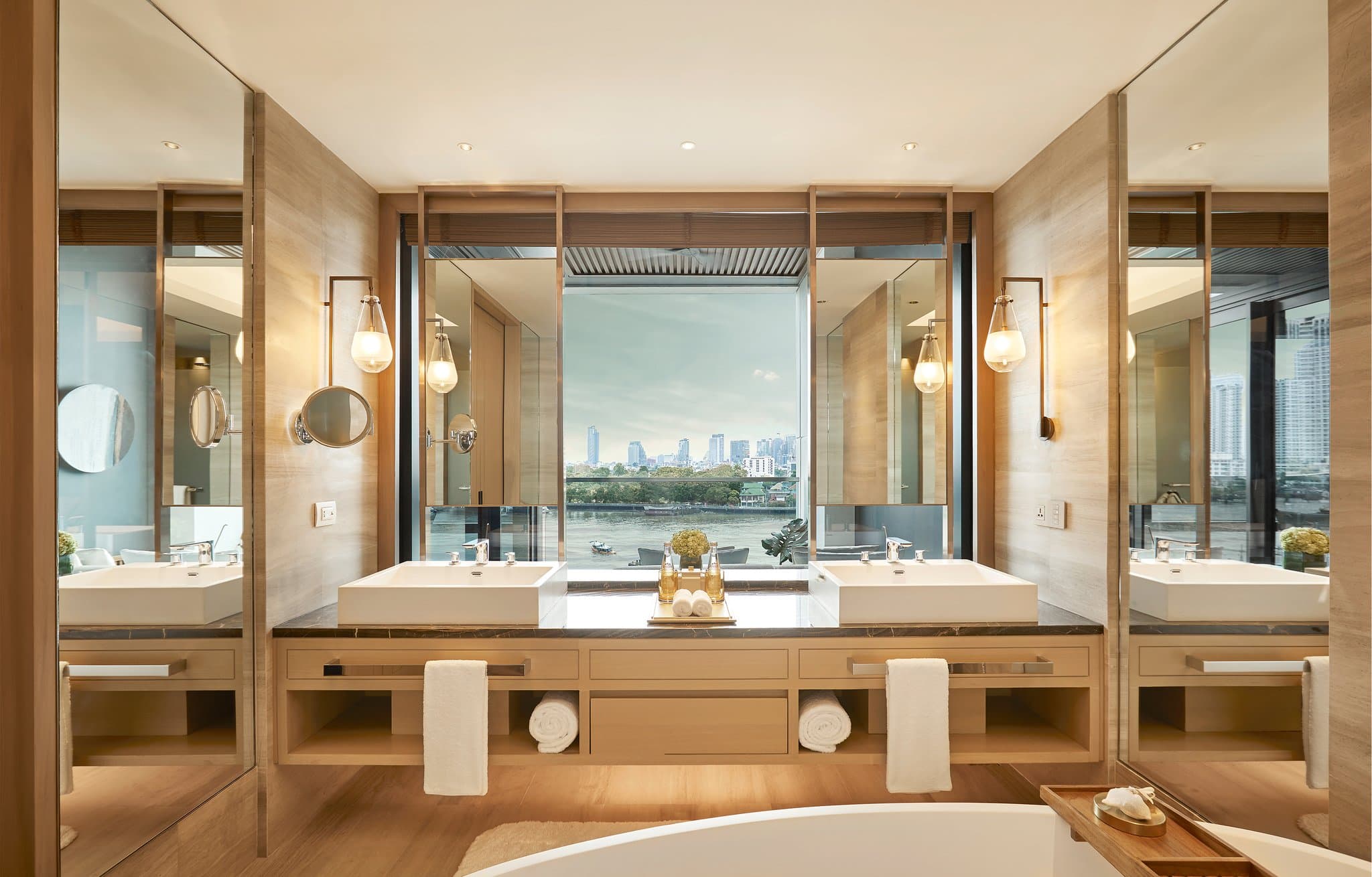 View of Capella Bangkok's riverfront villas with private plunge pools overlooking the Chao Phraya River at sunset.