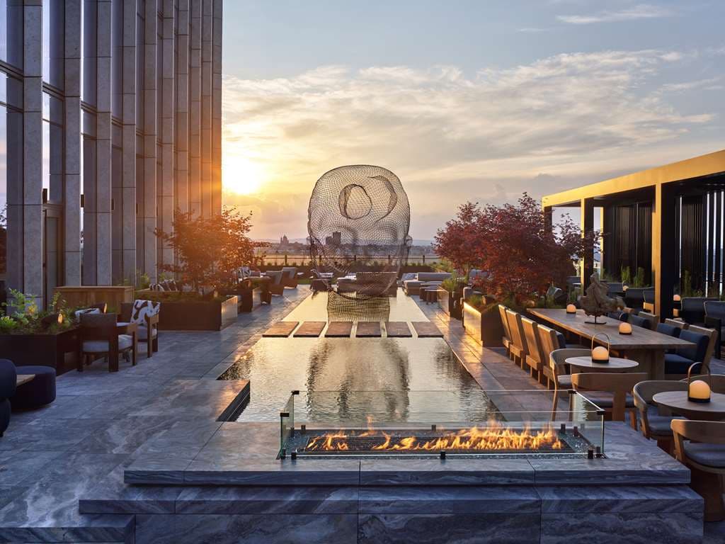 해질녘 Equinox Hotel New York의 야외 온수 수영장과 뒤로 보이는 거대한 베슬(Vessel) 구조물.
