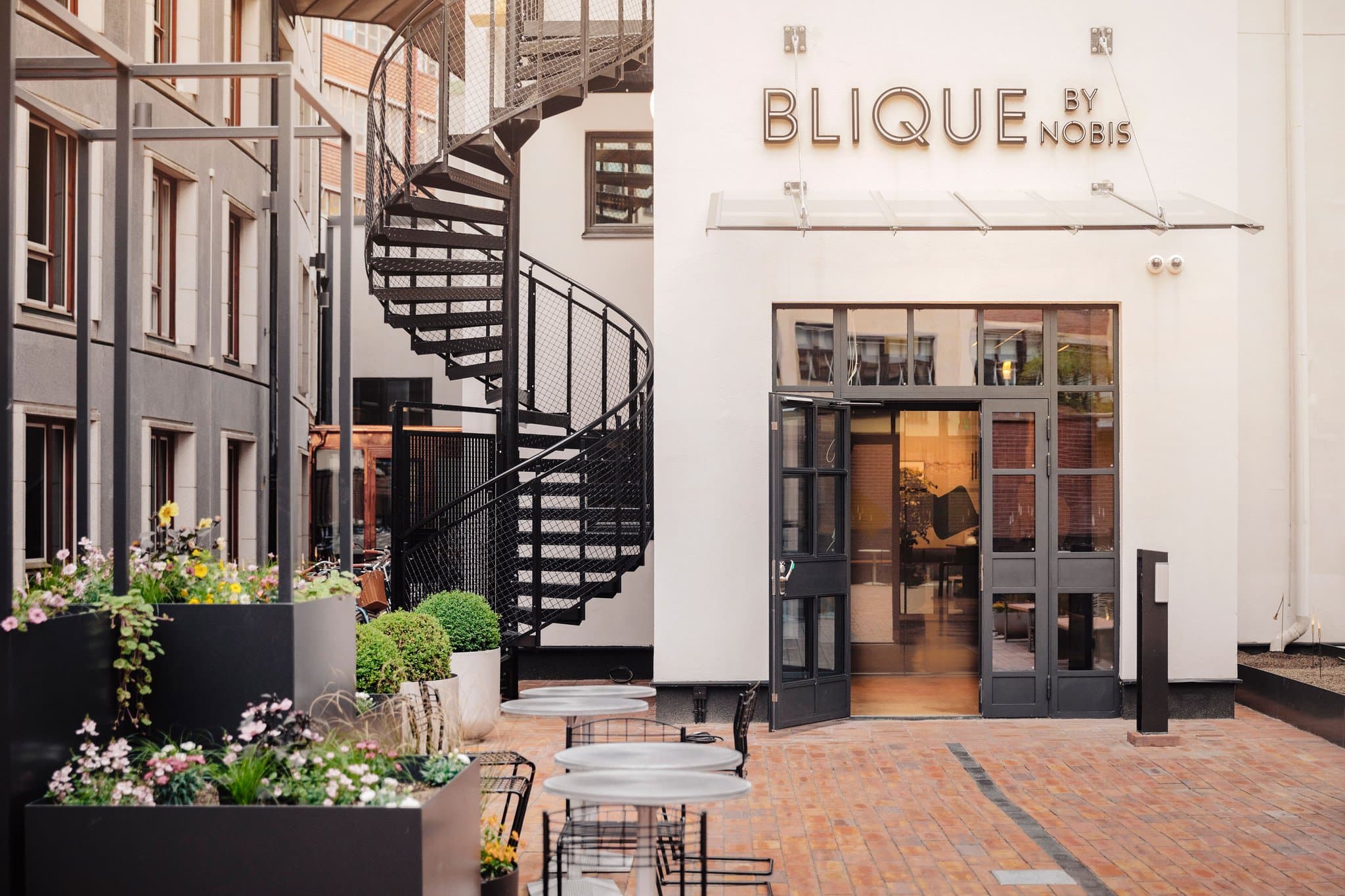 The outdoor terrace of Arc Rooftop at Blique by Nobis featuring modern lounge seating and a backdrop of the Norra Tornen skyscrapers.