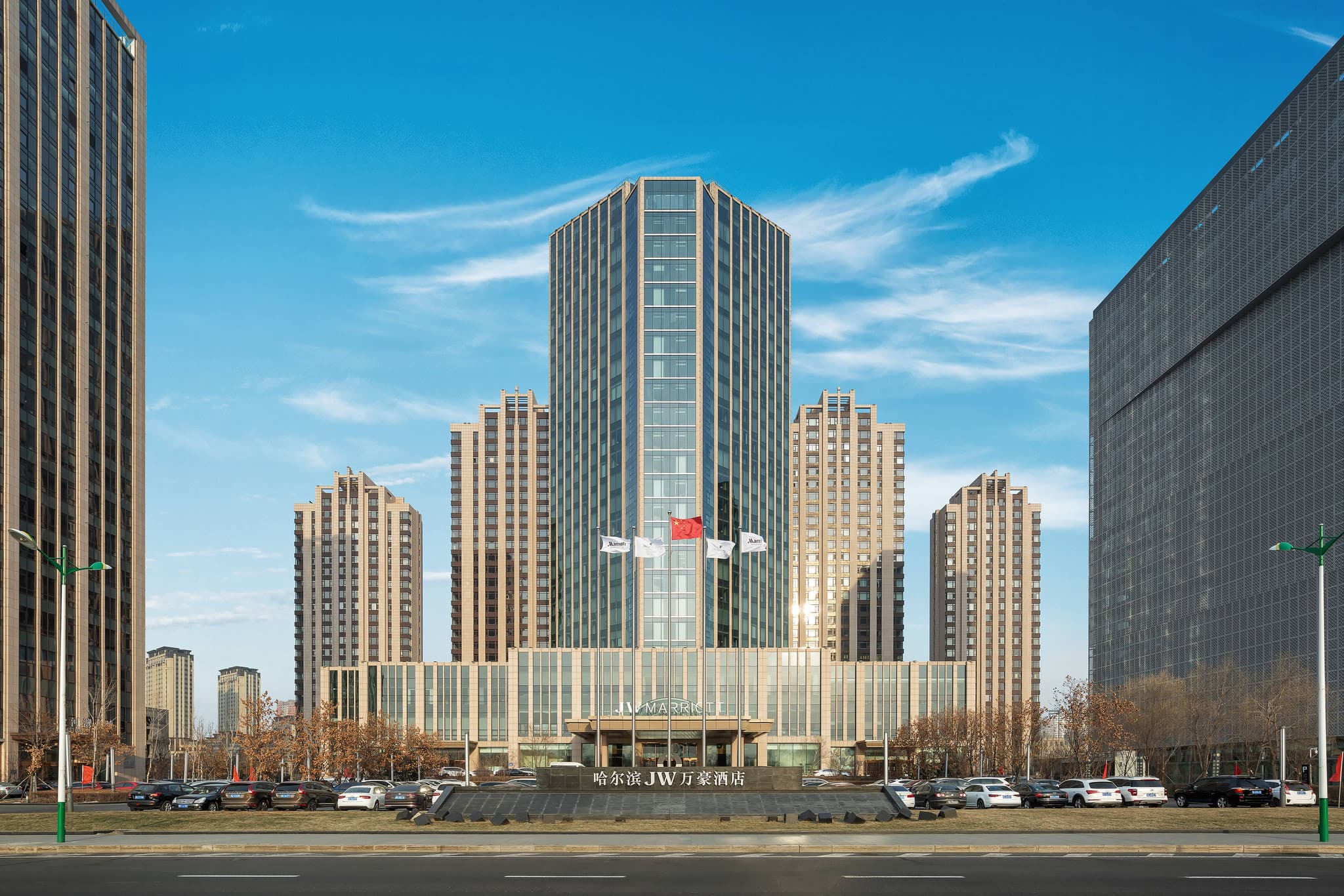 View from a JW Marriott Harbin room featuring floor-to-ceiling windows overlooking the frozen Songhua River and distant ice festival lights.