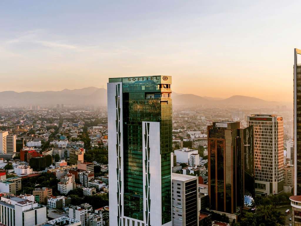 View from Cityzen Rooftop Kitchen at Sofitel Mexico City Reforma looking out over the Angel of Independence and Paseo de la Reforma at twilight.
