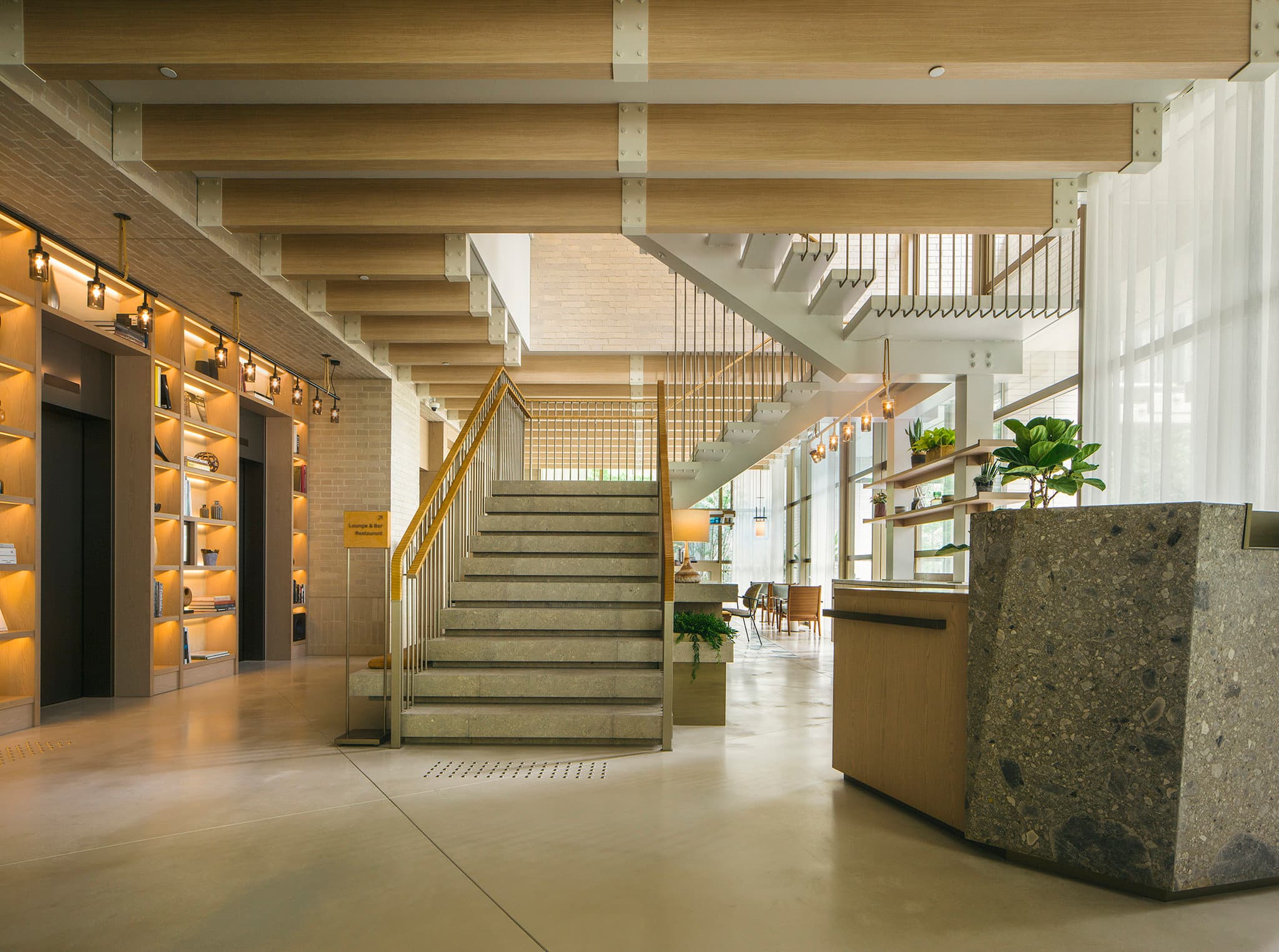 The dramatic blue limestone staircase at Zentis Osaka, framed by raw concrete columns and warm brass lighting.