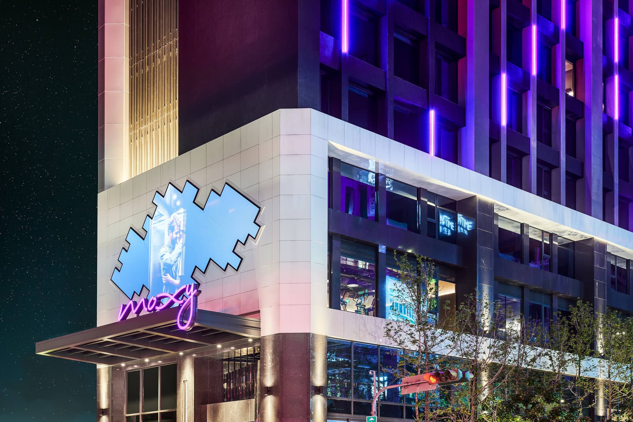 Neon-lit Rooftop XOXO bar at Moxy Taichung featuring a stylized betel nut stand booth and outdoor terrace seating at night.