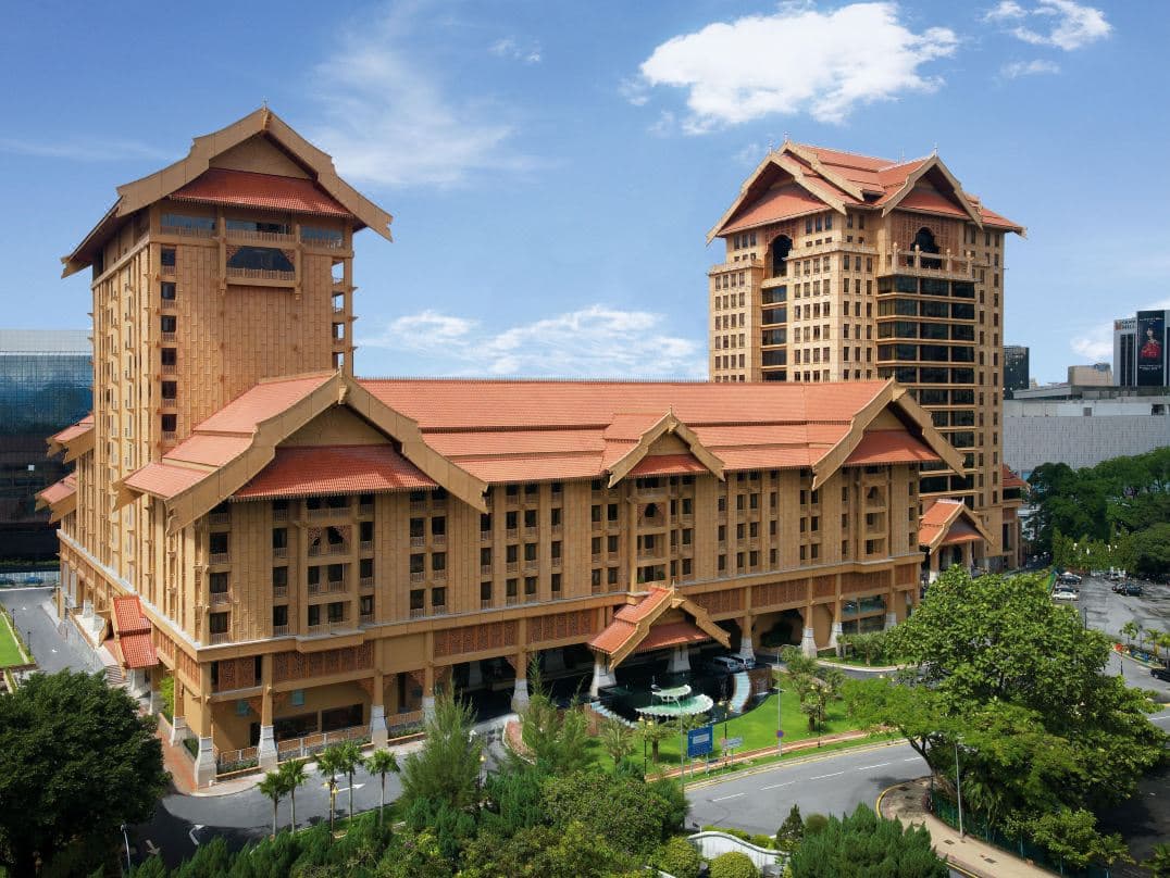 The Royale Chulan Kuala Lumpur outdoor swimming pool featuring a large man-made waterfall and traditional Malay architectural facade.