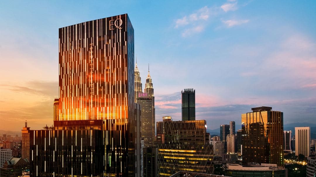 Infinity pool at EQ Kuala Lumpur Level 29 with direct view of KL Tower at sunset.