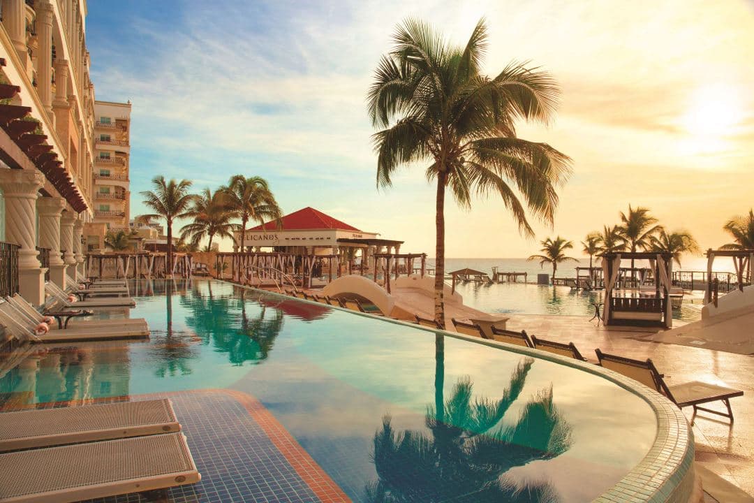 A dramatic symmetry shot of the Hyatt Zilara infinity pool bridge at sunset, framing the Caribbean Sea.