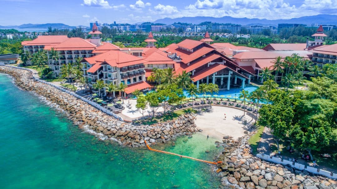 The Magellan Sutera Resort's grand longhouse-style lobby featuring high timber beams and open-air architecture overlooking the pool and South China Sea.