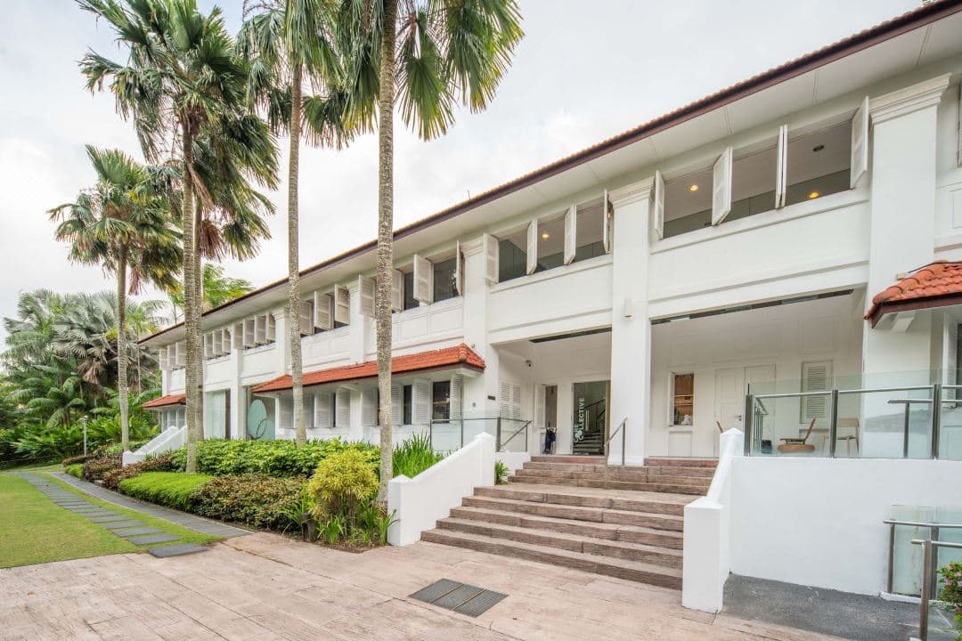 The 45m Larkhill Terrace infinity pool at Amara Sanctuary Resort Sentosa, framed by restored white colonial barracks and lush tropical greenery.