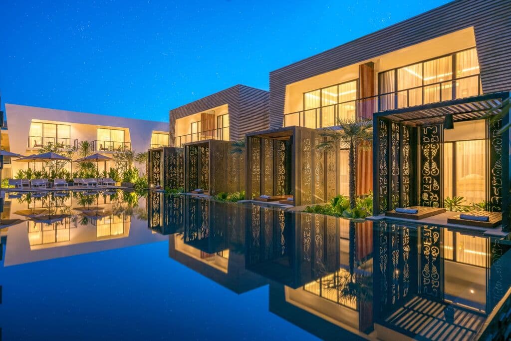 Metta Residence 시엠립의 프라이빗 풀 빌라, 해질녘 랜턴 조명과 해수 수영장에 비친 열대 식물.