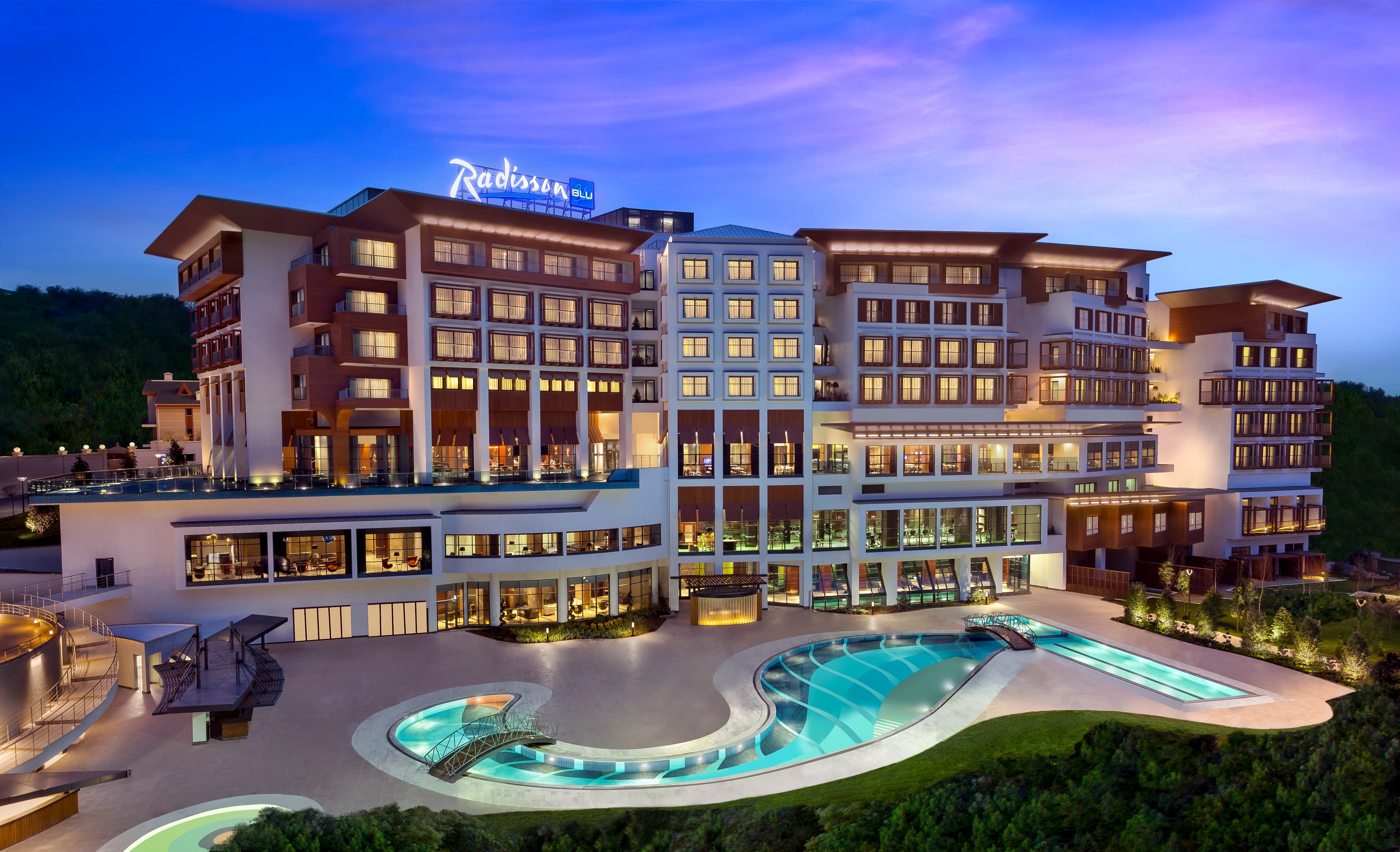 Wide angle view of the Elysia Spa indoor pool at Radisson Blu Tuzla, featuring modern lighting and lounge chairs.