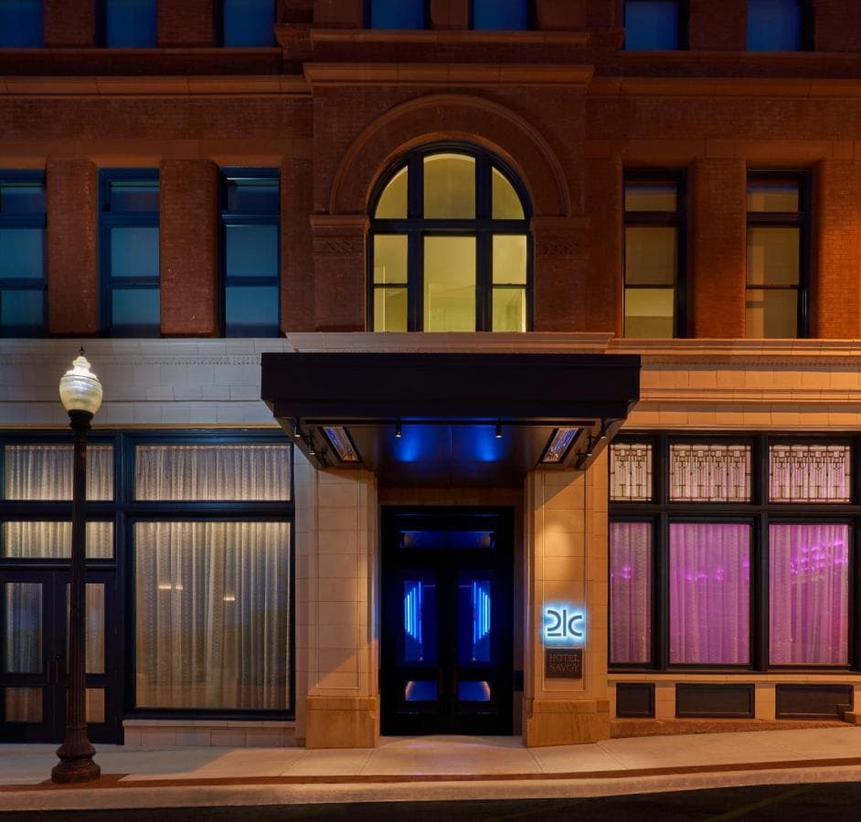 The Hotel Savoy Kansas City lobby featuring the historic stained glass dome and a modern green chandelier.
