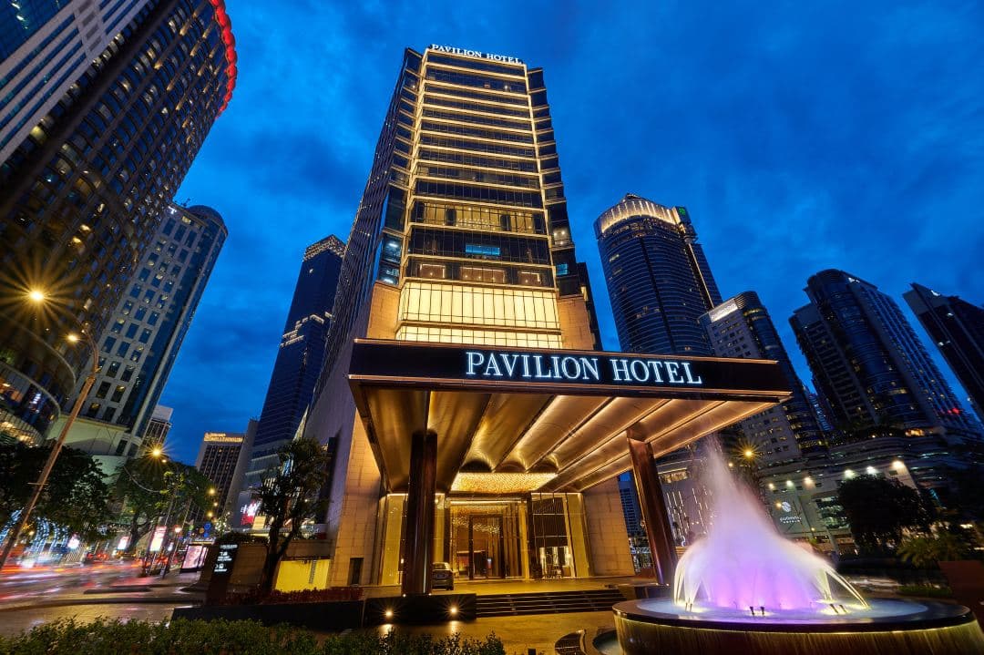 The rooftop infinity pool at Pavilion Hotel Kuala Lumpur at dusk, overlooking the glittering city skyline.