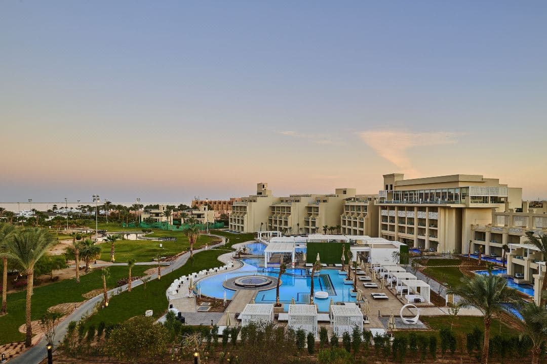 A sleek, all-white swim-up suite terrace at Steigenberger Pure Lifestyle with a private jacuzzi and pool access, set against a bright blue sky.