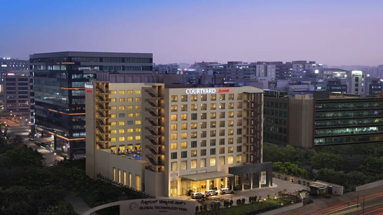 Twilight view of BG's Poolside Bar at Courtyard Bengaluru Outer Ring Road with illuminated blue pool and modern seating.