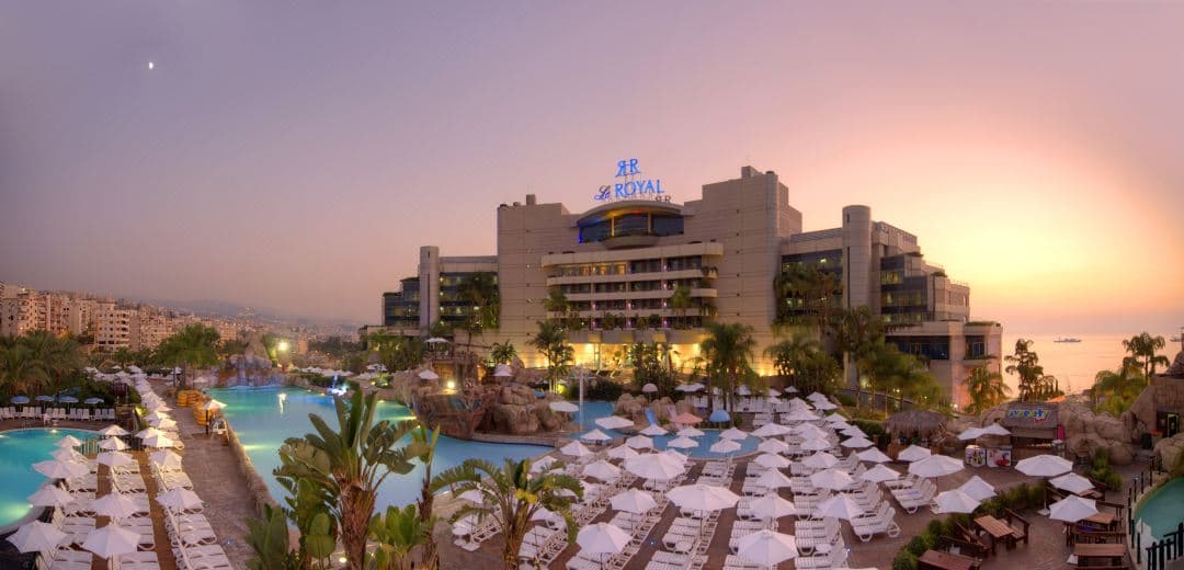 Le Royal Hotel Beirut's expansive pool deck overlooking the Mediterranean Sea, featuring the WaterGate Aqua Park slides in the distance.