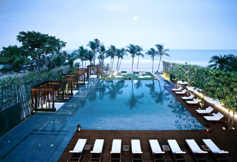 A wooden deck with a private plunge pool at twilight, overlooking the Hua Hin coastline.