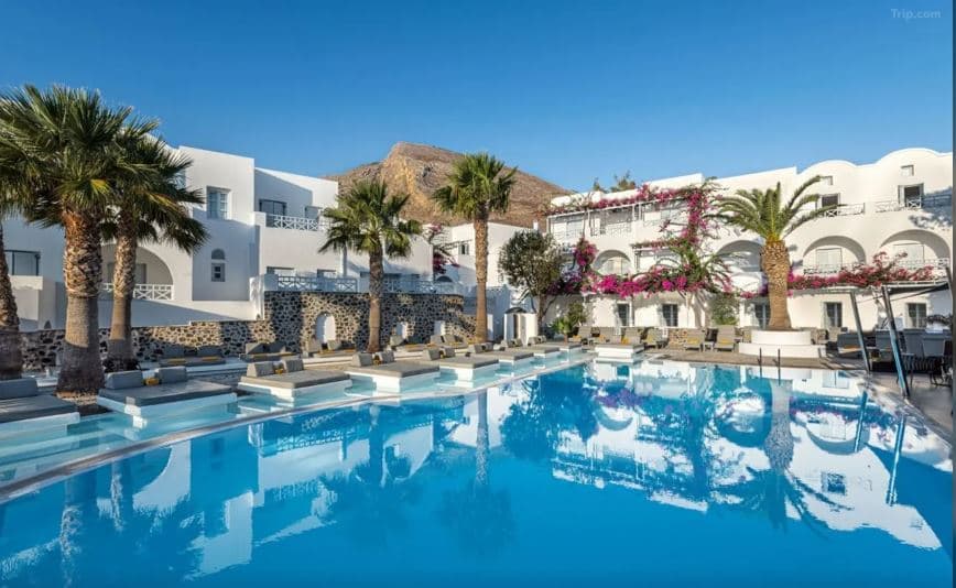 Santorini Kastelli Resort swim-up suites at night with illuminated turquoise pools and white Cycladic architecture.