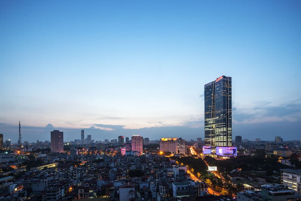 A guest standing on the glass-bottom Sky Walk at Lotte Hotel Hanoi, 65 floors above the city streets.
