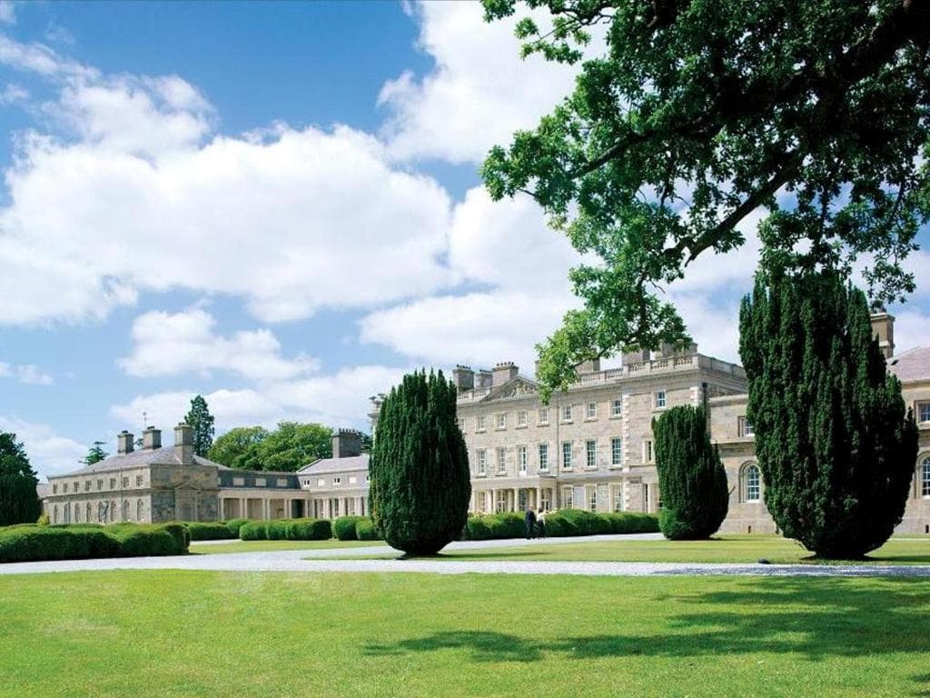 The Morrison Room at Carton House featuring high curved ceilings, Greek Corinthian columns, and modern dining tables set for dinner.