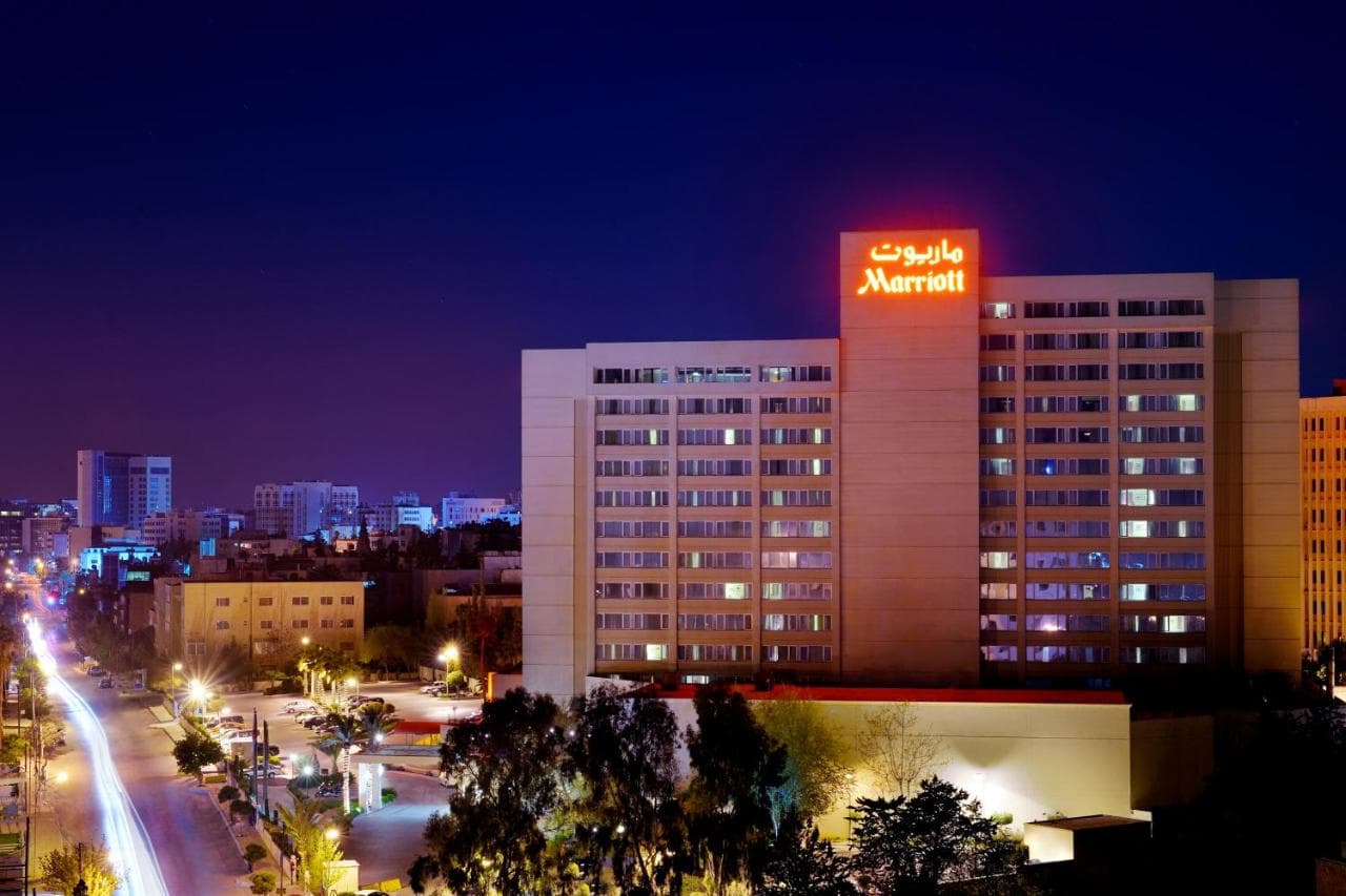 The Library Lounge at Amman Marriott featuring dark wood paneling, leather chesterfield sofas, and a warm, dimly lit ambiance.
