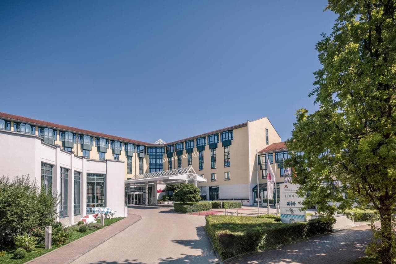 A sunlit, wood-paneled Bavarian terrace at the Munich Airport Marriott, overlooking the distant spires of Freising Cathedral.
