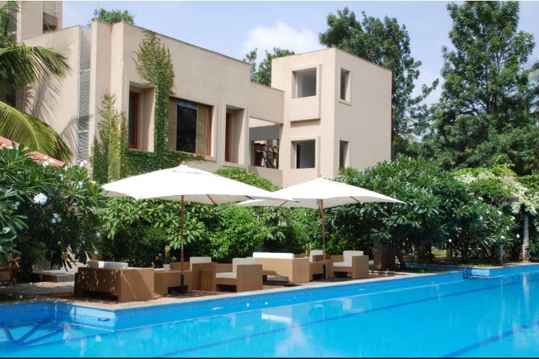 Shreyas Retreat infinity pool surrounded by dense coconut palms and tropical greenery.