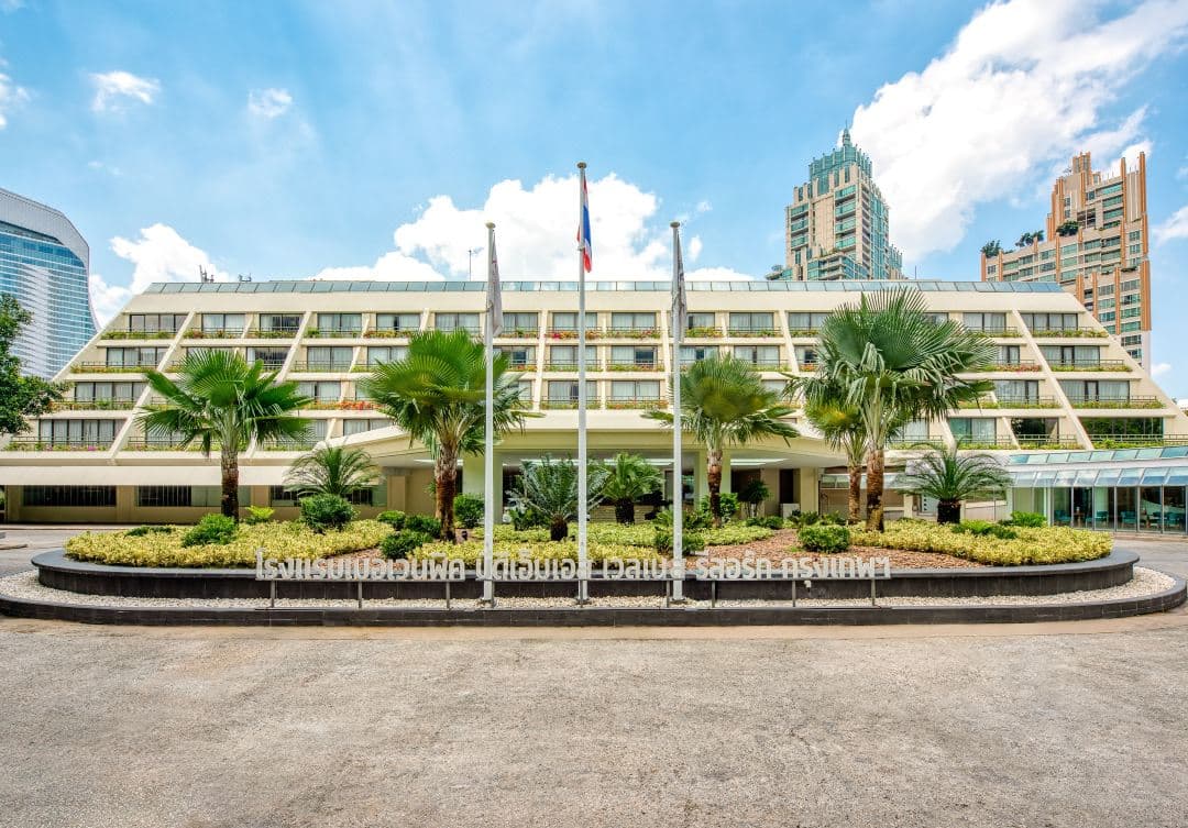 A free-form saltwater swimming pool surrounded by dense tropical trees and century-old gardens at Mövenpick BDMS Wellness Resort Bangkok.