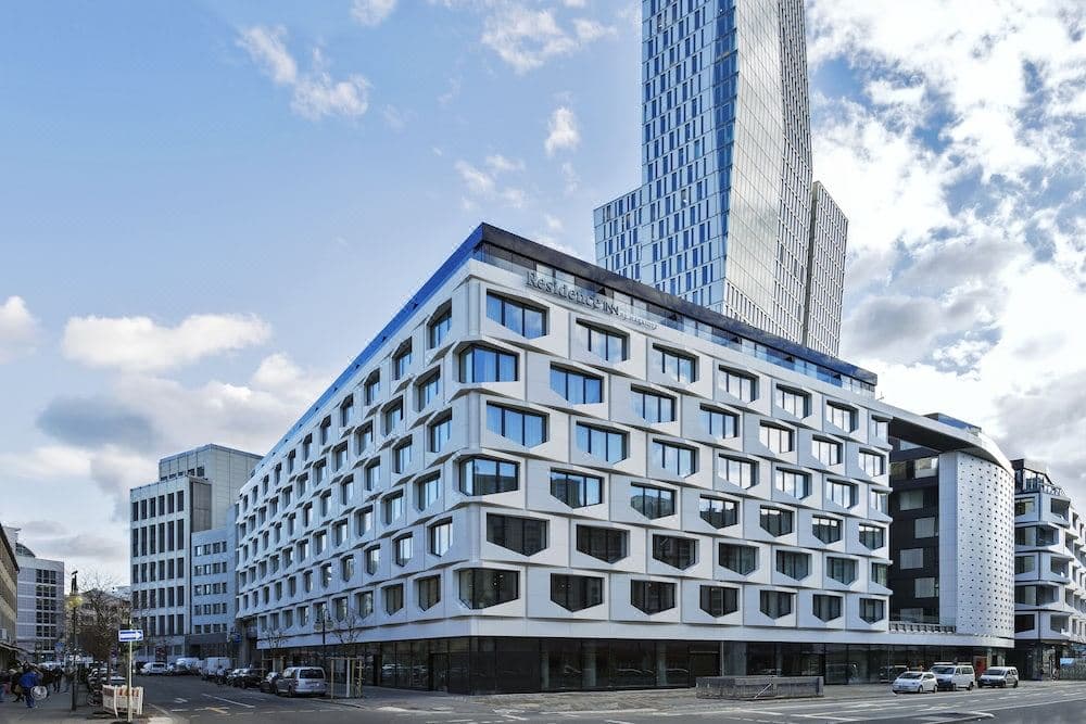 A modern studio suite at Residence Inn Frankfurt featuring a kitchenette and a private terrace overlooking the city skyline.