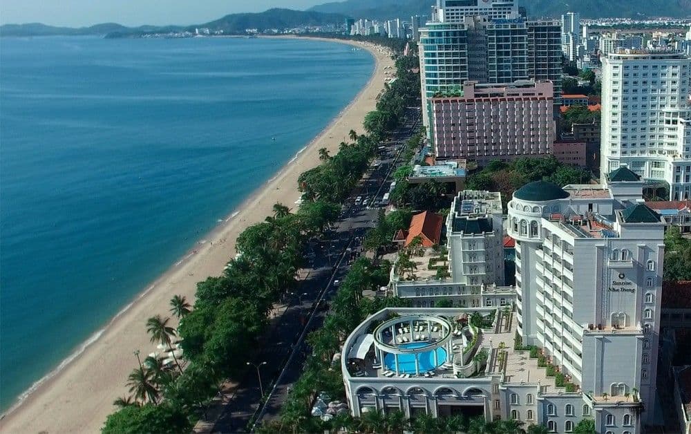 A low-angle shot of the Sunrise Nha Trang's white colonial façade featuring pillared balconies and a Roman-style swimming pool courtyard.