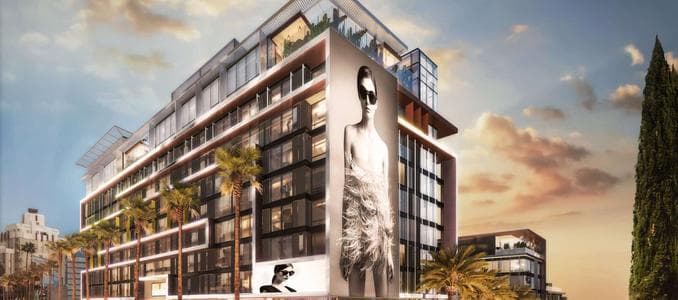 Rooftop pool deck at The Sun Rose West Hollywood with pink and teal loungers, guests dining at Merois, and panoramic Los Angeles skyline views.