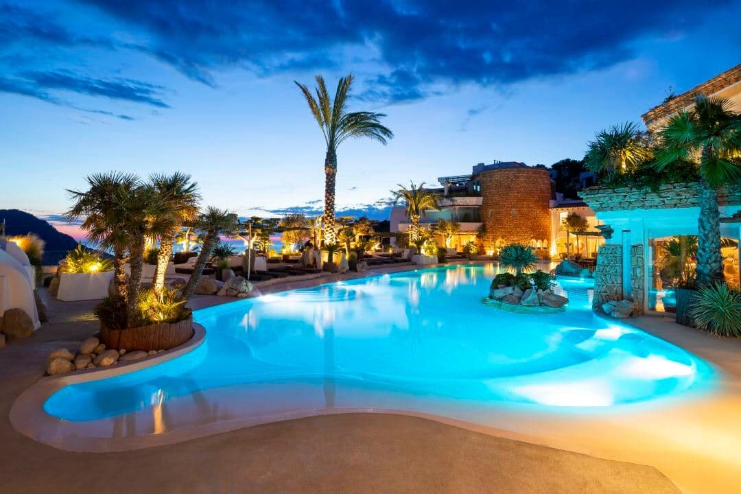 Hacienda Na Xamena 酒店的悬浮瀑布池,客人在日落时分享受海水理疗,背景是壮丽的悬崖海景。