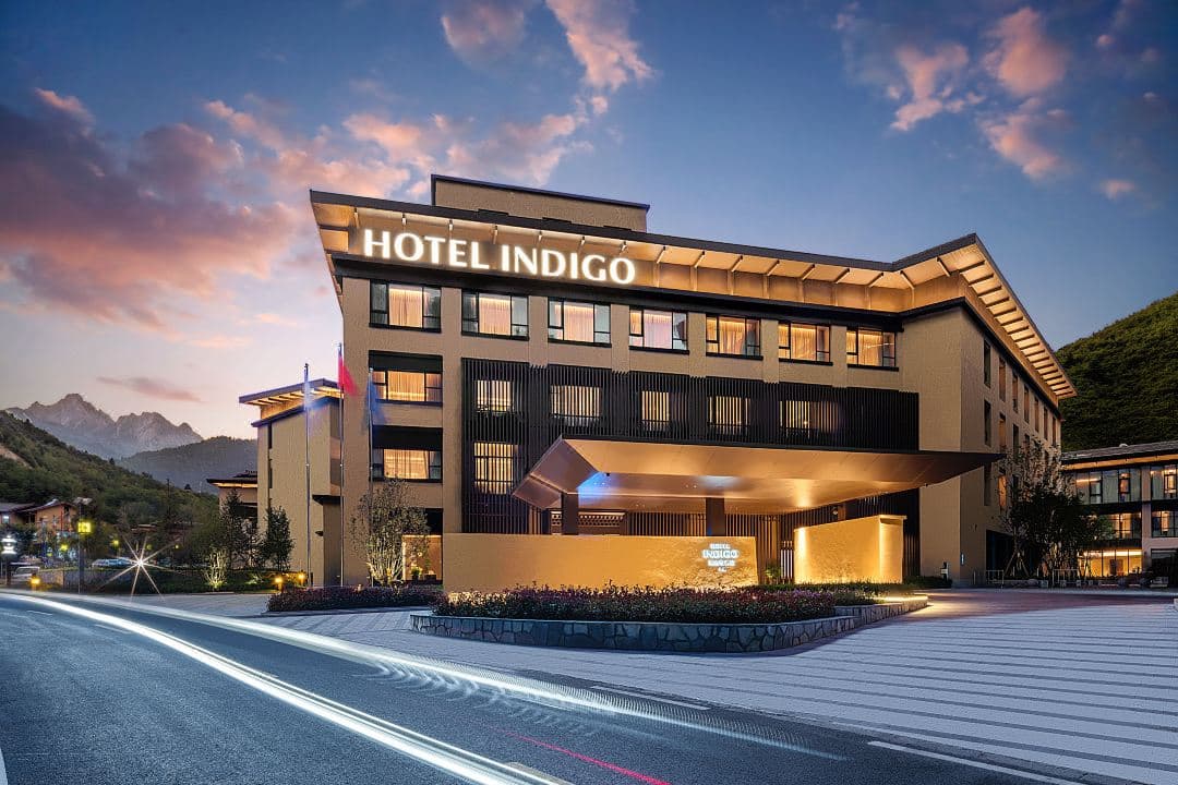 Lobby of Hotel Indigo Jiuzhai featuring a dramatic eagle-wing ceiling design and a central fireplace surrounded by modern Tibetan decor.