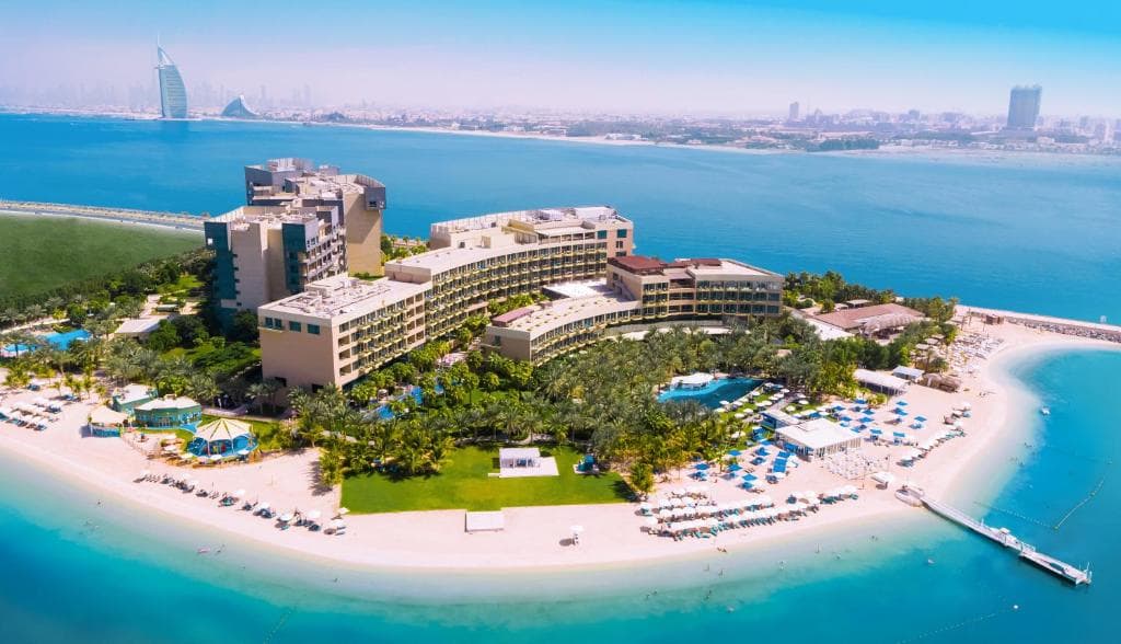 Sunset view from Rixos The Palm East Crescent featuring the Dubai Marina skyline and resort pool.
