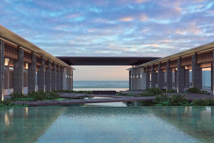 Massive carved wooden doors opening to the Conrad Tulum open-air lobby with ocean views.