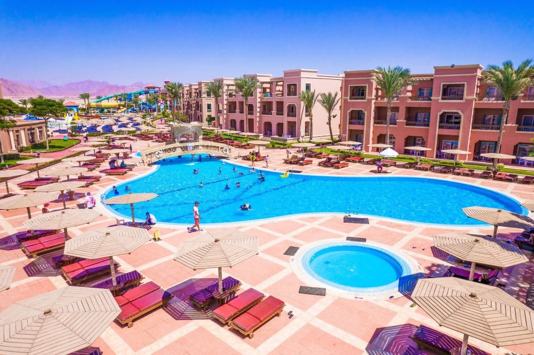 Aerial view of the massive Charmillion Aqua Park with colorful slides winding into blue pools, set against the arid Sinai mountains.