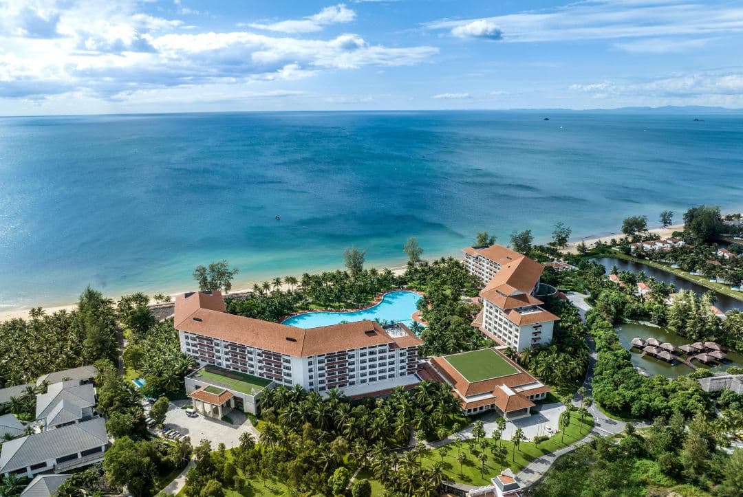 Aerial view of Vinpearl Resort & Spa Phu Quoc showing the massive central lagoon pool winding towards the white sand beach and red-roofed villas.