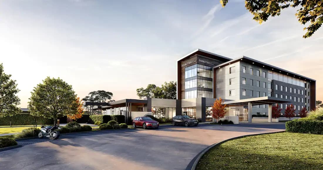 Exterior of DoubleTree Karaka featuring manicured lawns, outdoor fire pits at the Horseshoe Bar, and modern architectural design.