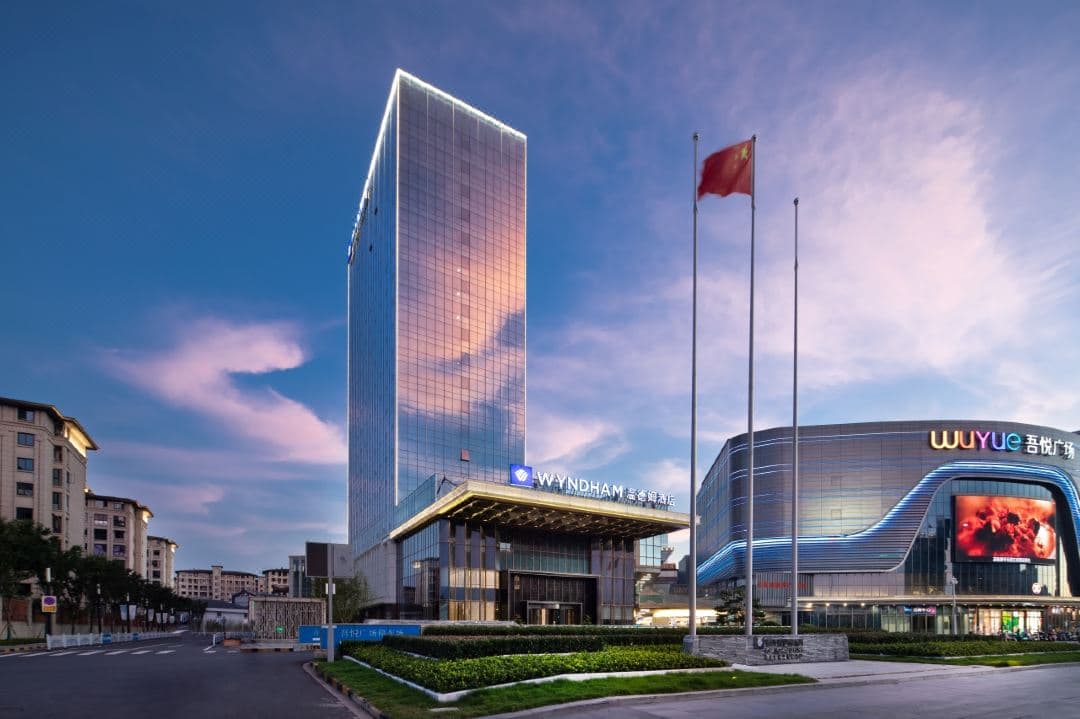 A sleek, modern hotel suite at Wyndham Liyang with floor-to-ceiling windows overlooking Yanshan Park, featuring a plush king bed and minimalist decor.
