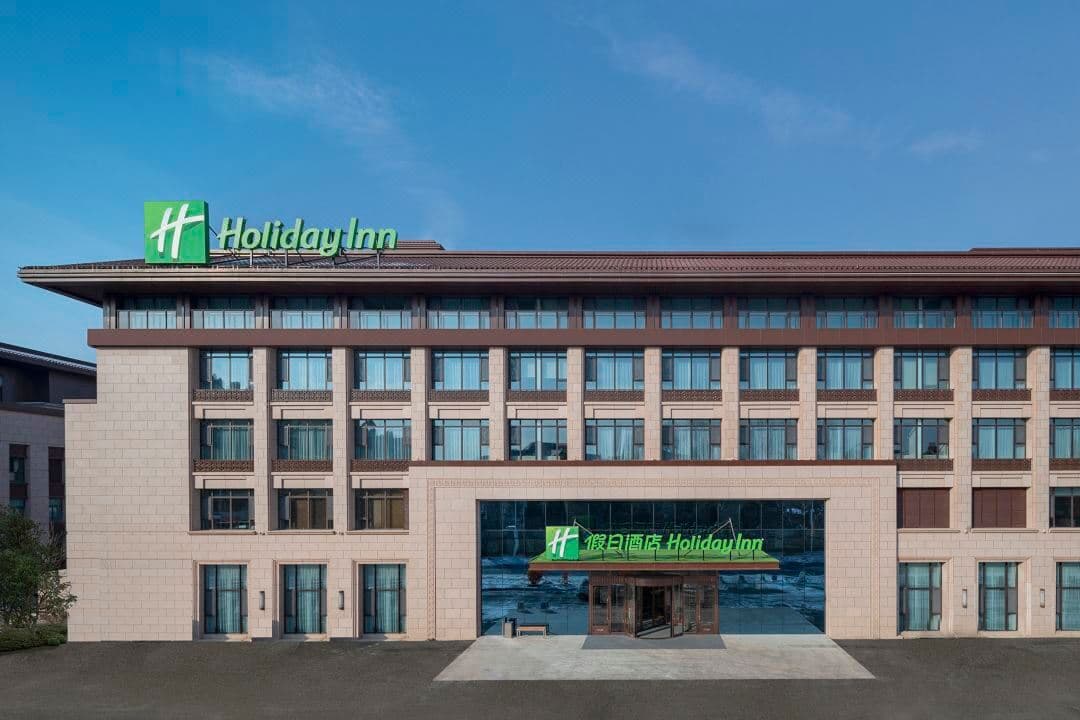 Spacious guest room at Holiday Inn Changchun Jingyue featuring modern decor and large windows looking out to the winter cityscape.