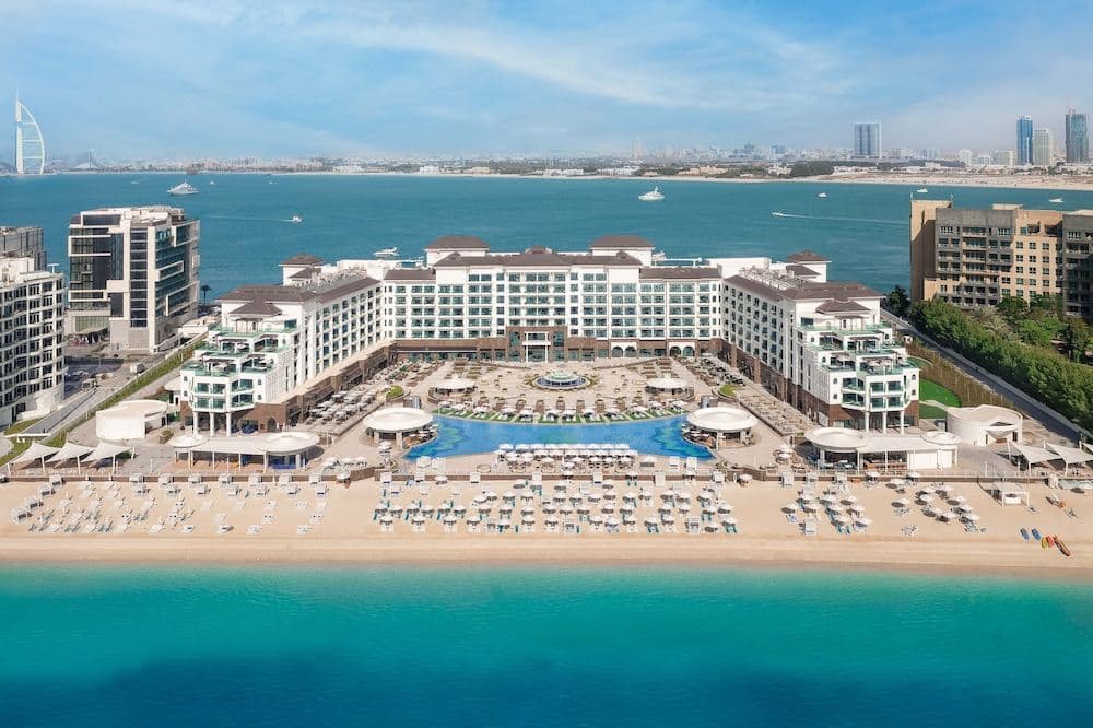 The Taj Exotica's 70-meter Olympic-sized pool stretching towards the Arabian Gulf, flanked by white loungers and palm trees.
