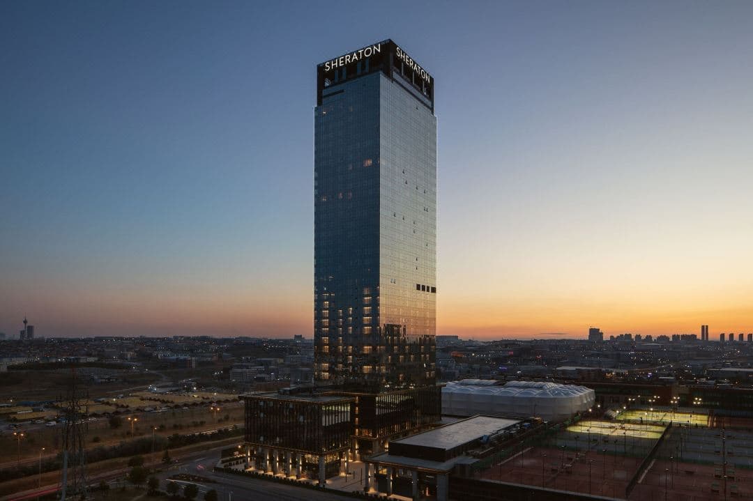 Sheraton Istanbul Esenyurt 18th-floor indoor pool with panoramic city skyline views through floor-to-ceiling windows.