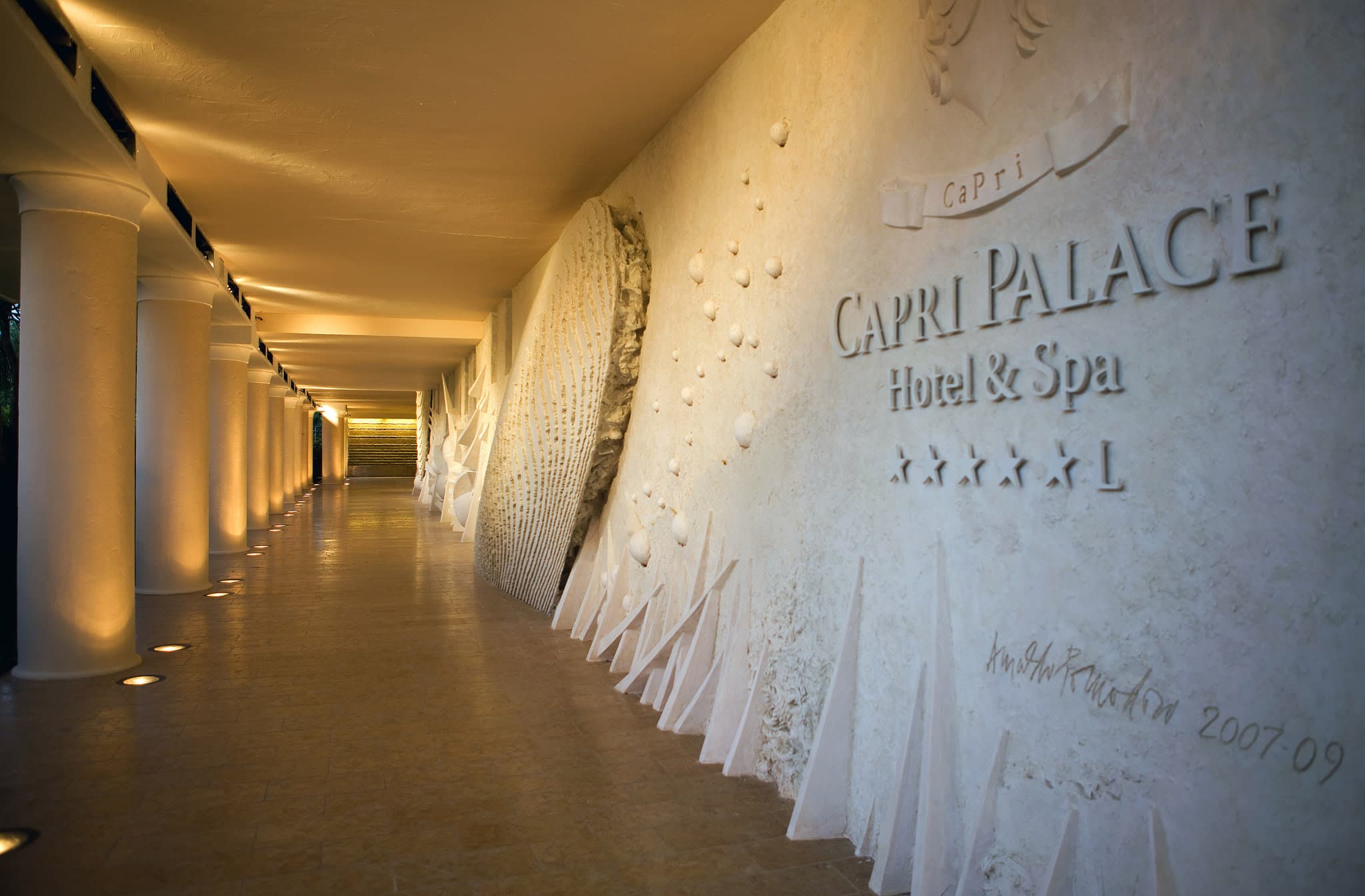 The 40m mosaic pool at Capri Palace Jumeirah features an Arnaldo Pomodoro seabed sculpture, surrounded by white loungers.