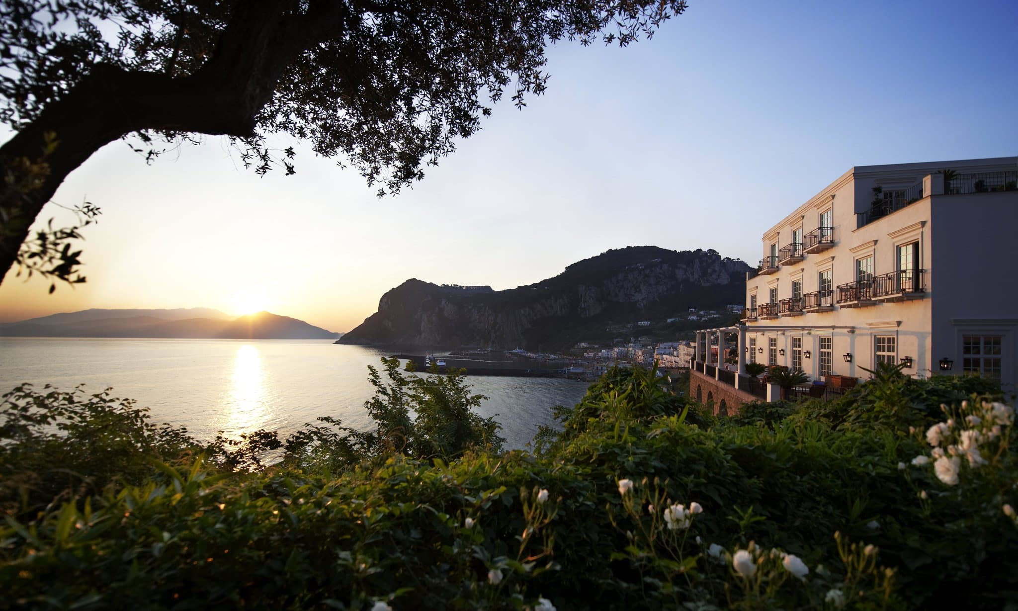 J.K. Place Capri terrace featuring white Doric columns and navy blue loungers overlooking the Gulf of Naples.