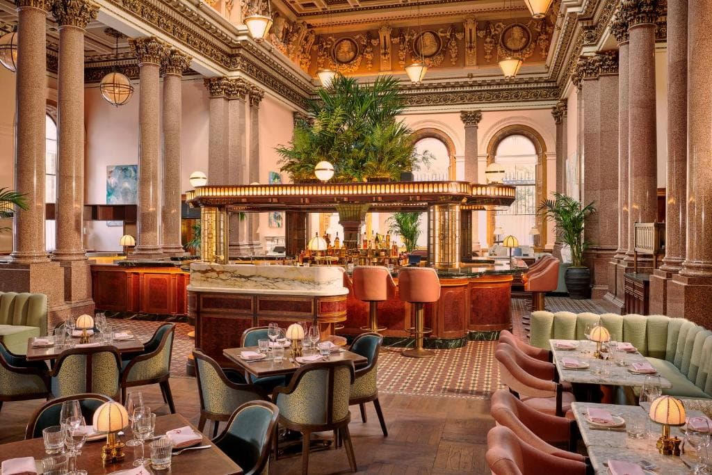 The Spence restaurant at Gleneagles Townhouse featuring a grand glass dome, Peterhead granite columns, and a central U-shaped bar with mint green seating.