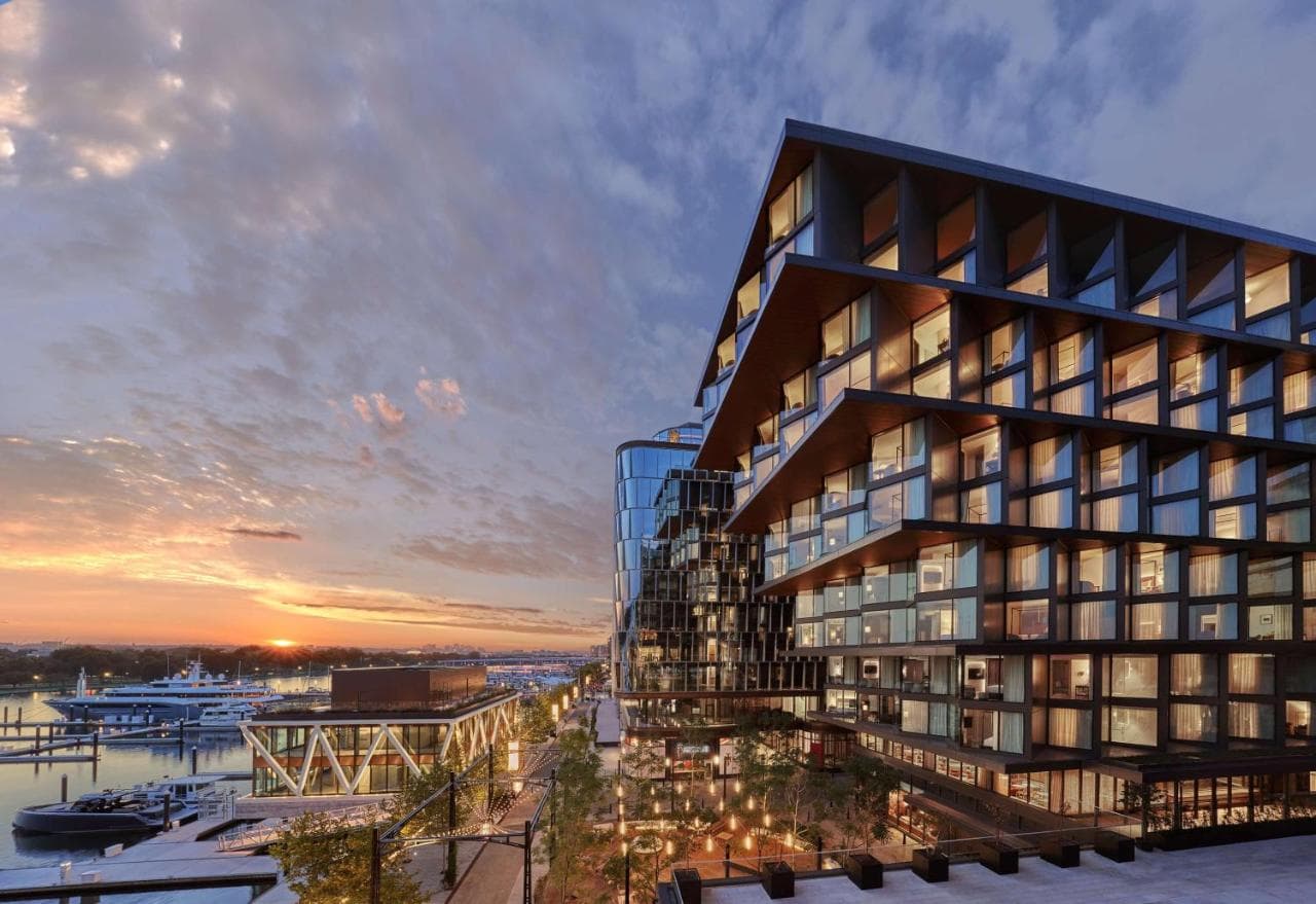 A stylish rooftop bar at Moonraker with a circular brass lighting fixture and panoramic views of the Potomac River at sunset.